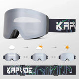 Photochromic snow goggle with a dark grey frame, black face foam and a silver photochromic lens, on a black strap with a grey-and-green loop graphic and white brand lettering. Three small goggles show the lens going to a bright silver mirror from cloud to sun.