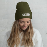 Woman wearing the olive Skeezy cuffed beanie with white SKEEZY embroidery