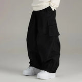 Sidehit Baggy Cargo Snow Pant in Black, side view on a grey background, showing the wide leg, snap-flap thigh cargo pocket and elasticated cuffs